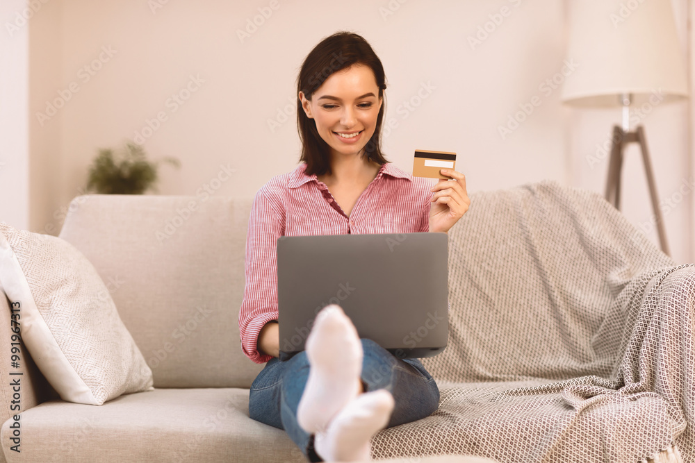 Online Banking. Satisfied girl making purchases on internet using laptop and credit card to pay, sitting on sofa Online Banking. Satisfied girl making purchases on internet using laptop and credit card to pay, sitting on sofa