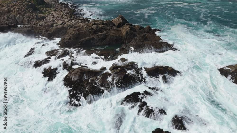 Aerial View Of Powerful waves are crashing against a rocky shore, creating a dramatic scene of nature's power Aerial View Of Powerful waves are crashing against a rocky shore, creating a dramatic scene of nature's power