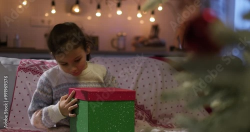 Excited kid opening gift box. Cute girl unwrapping Christmas surprise and expressing amazement. Merry xmas New Year love concept