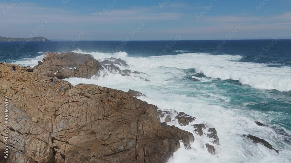 Dynamic aerial view capturing powerful waves crashing against rocks at Playa Chica in Quintay, showcasing the stunning coastline of Casablanca, Valparaíso, Chile. Dynamic aerial view capturing powerful waves crashing against rocks at Playa Chica in Quintay, showcasing the stunning coastline of Casablanca, Valparaíso, Chile.