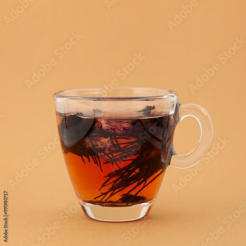 Medicinal herbal tea of Dried Rhodiola quadrifida or Red brush plant, also called as Siberian ginseng. Transparent cup, side view. Drink used to support mental and physical endurance photo