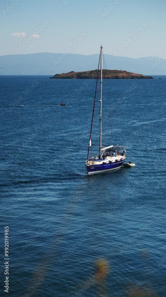 A sailboat is captured cruising in calm blue waters with a distant island and a clear sky in the background. The vibrant blue sea and the tranquil atmosphere create a peaceful and adventurous spirit A sailboat is captured cruising in calm blue waters with a distant island and a clear sky in the background. The vibrant blue sea and the tranquil atmosphere create a peaceful and adventurous spirit