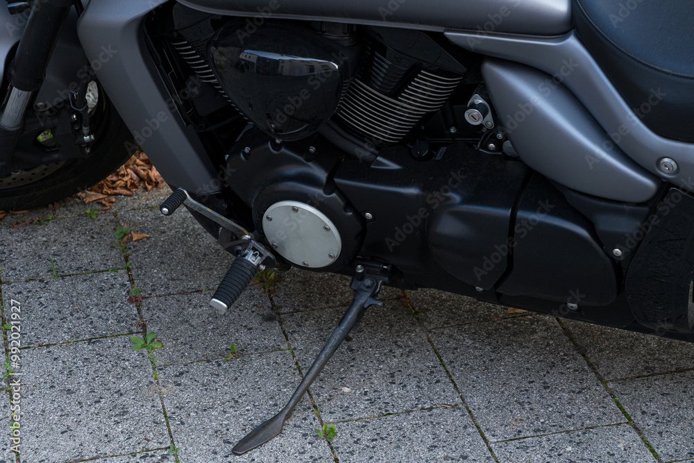 Close-up of a motorcycle engine and footpeg on a gravel driveway Close-up of a motorcycle engine and footpeg on a gravel driveway
