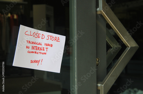 Sign posted on glass door reads: Sorry, we are closed due to a lack of internet connection. We apologize for the inconvenience. Business and Technology .