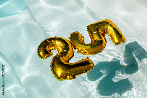 Golden inflatable number 30 floating in a clear swimming pool photo