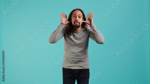 Portrait of spiteful man making exaggerated silly faces, mimicking someone, doing mocking gesturing. Person making goofy facial expressions, being playful, making fun, studio background, camera A