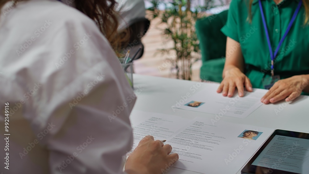 HR staff going through the selection process phase of the recruitment activity, choosing the best applicant based on their qualifications in the resume. Recruiters seeking talent. Camera B.