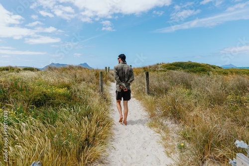 Man walking on sandy path amongst san dunes in Bream Bay, Northland, New Zealand.