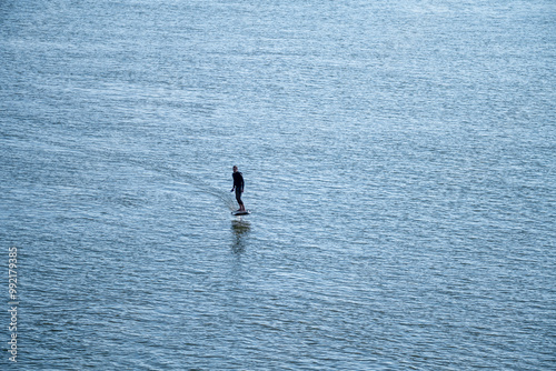 Silhouetted man on a hydrofoil surfboard