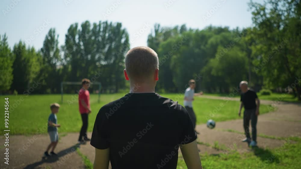 A middle-aged man throws a ball to his son during a lively outdoor soccer session, the son skillfully kicks the ball to his grandfather, who kicks the ball away