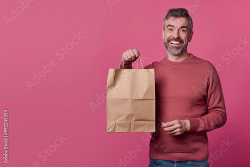 Mature man shopping for Black Friday deals showing off stylish shopping bag in a trendy and modern fashion