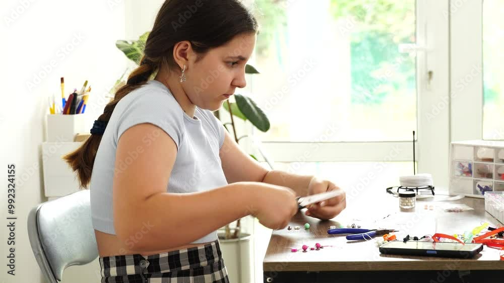Teenage girl makes jewelry with beads, hobby leisure Teenage girl makes jewelry with beads, hobby leisure