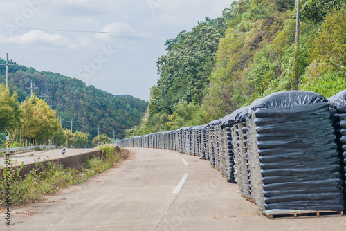 Plastic-covered bags of fertilizer stacked along a abandoned rural highway in rural South Korea photo