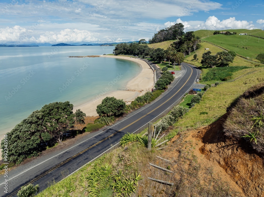 Calm ocean beach and country road hudding coastline in Maraetai, Auckland, New Zealand.
