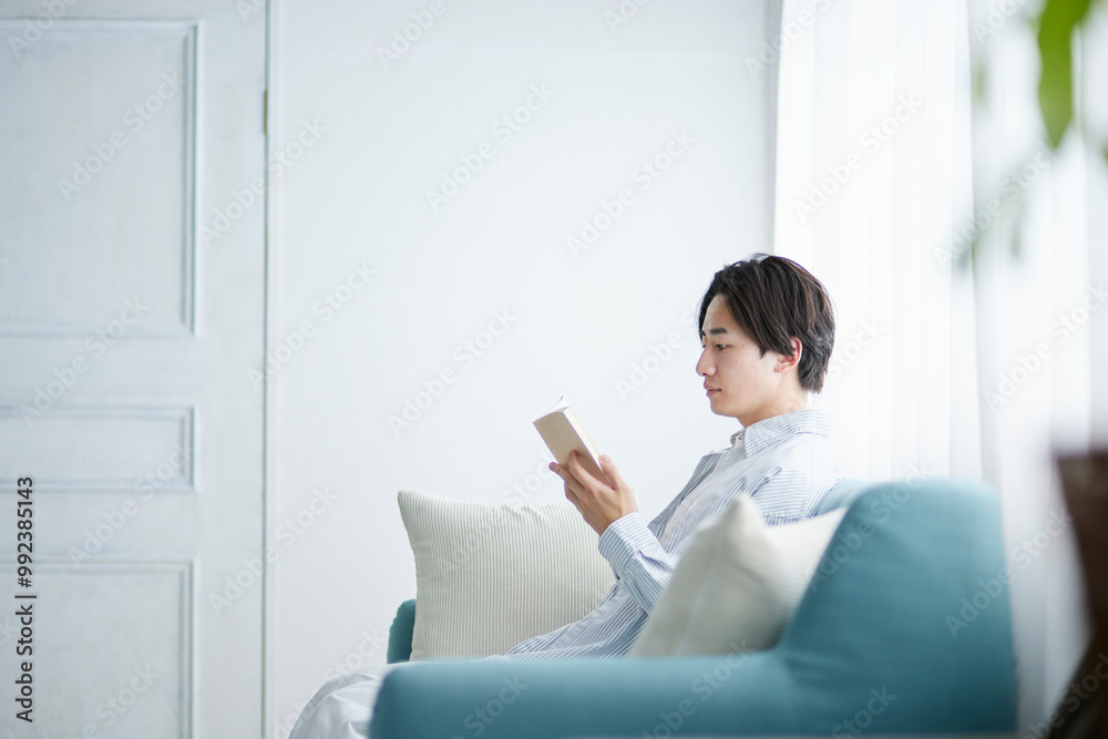 リビングのソファーリラックスし読書をする日本人の男性 リビングのソファーリラックスし読書をする日本人の男性