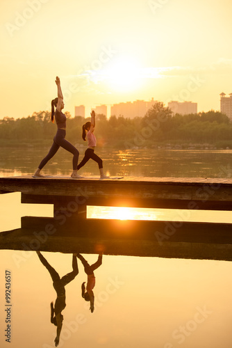 Mom And Daughter Doing Yoga In A Park