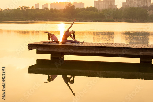 Mom And Daughter Doing Yoga In A Park