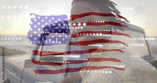 Image of american flag and stars over happy african american man by car on sunny beach