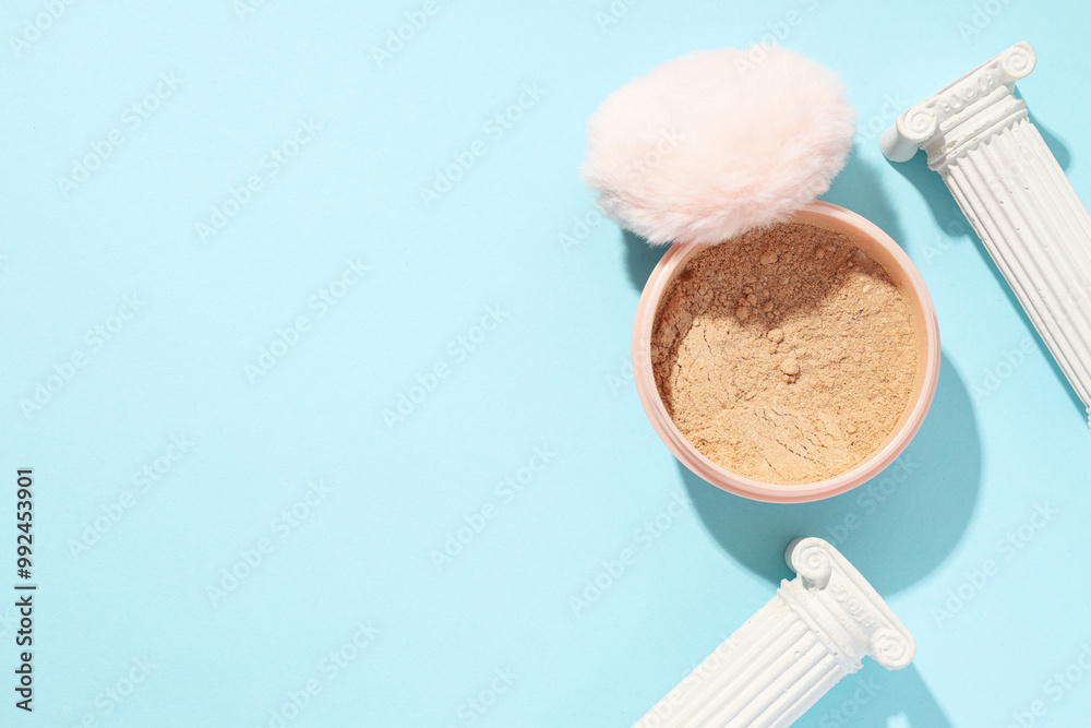 A bottle of loose powder, light shade, on a blue background.