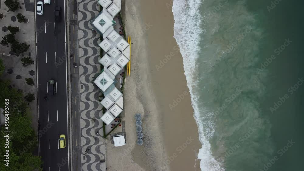 Visão aérea de 90 graus do trânsito de veículos, orla da praia e ondas em Copacabana, Rio de Janeiro, capturando a dinâmica urbana e a beleza costeira