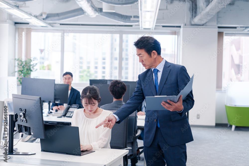 オフィスで上司から叱責をされる若い女性社員 オフィスで上司から叱責をされる若い女性社員