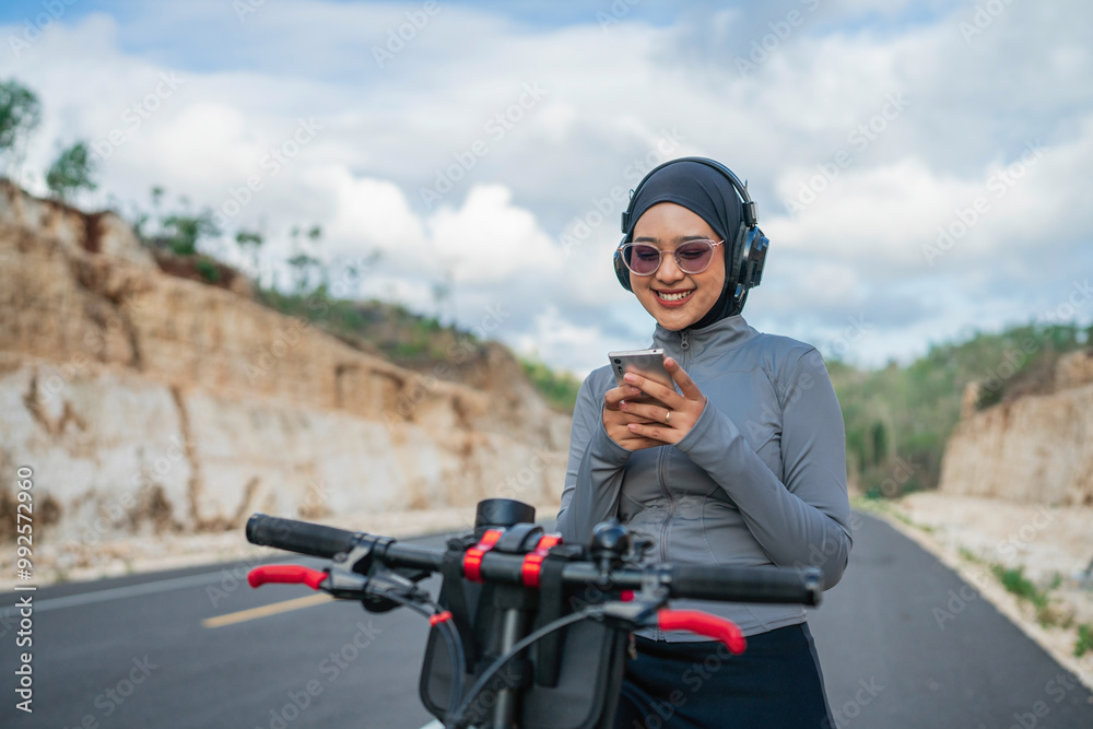hijab woman using phone when riding bike, biking concept hijab woman using phone when riding bike, biking concept