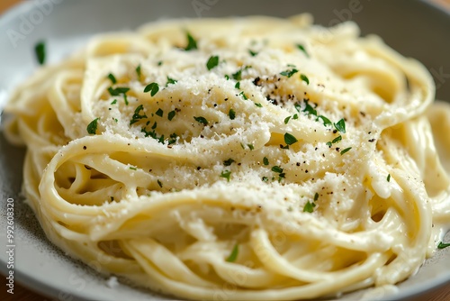 A close-up shot of fettuccine pasta, perfectly smooth and slightly creamy, topped with fresh Parmesan cheese