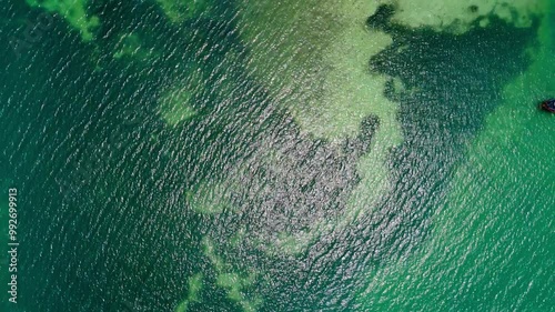 Drone flying through blue ocean water to a natural tropical island