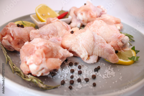 raw chicken wings with pepper and lemon on the plate