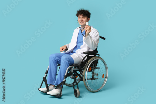 Young doctor on wheelchair holding stethoscope on blue background