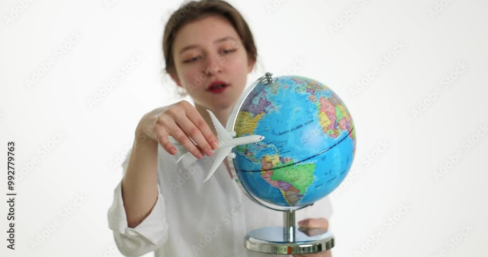 Pensive young woman holds massive Earth globe playing with toy aircraft slow motion. Lady promotes concept of travelling around world in light tourist agency Pensive young woman holds massive Earth globe playing with toy aircraft slow motion. Lady promotes concept of travelling around world in light tourist agency