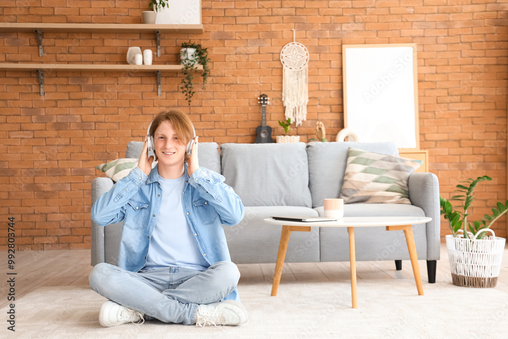 Redhead teenage boy in headphones sitting on floor at home Redhead teenage boy in headphones sitting on floor at home