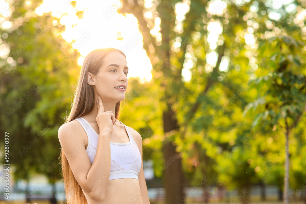 Sporty young woman counting pulse after training in park Sporty young woman counting pulse after training in park
