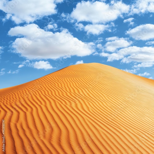  Beautiful desert dunes with orange sand and blue sky. The top of the dune is smooth, with ripples in the background