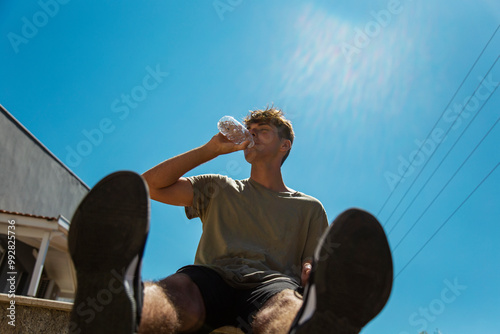 Young man sitting grinking water against blue sky background photo