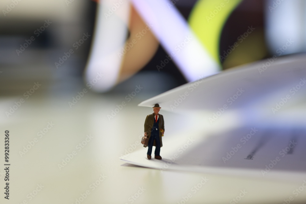 Micro person, business male with suitcase, standing under the page of paper in the office. Micro person, business male with suitcase, standing under the page of paper in the office.