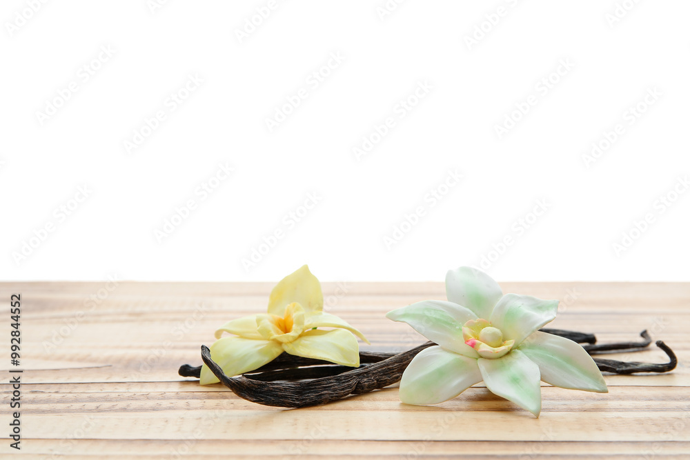 Fototapeta premium Aromatic vanilla pods and flowers on table against white background