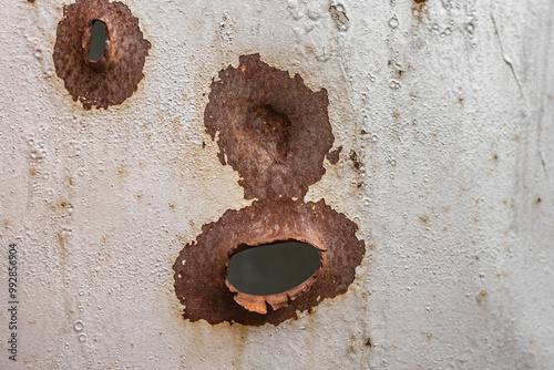 Gunshot holes in gray metal sheet, close-up.