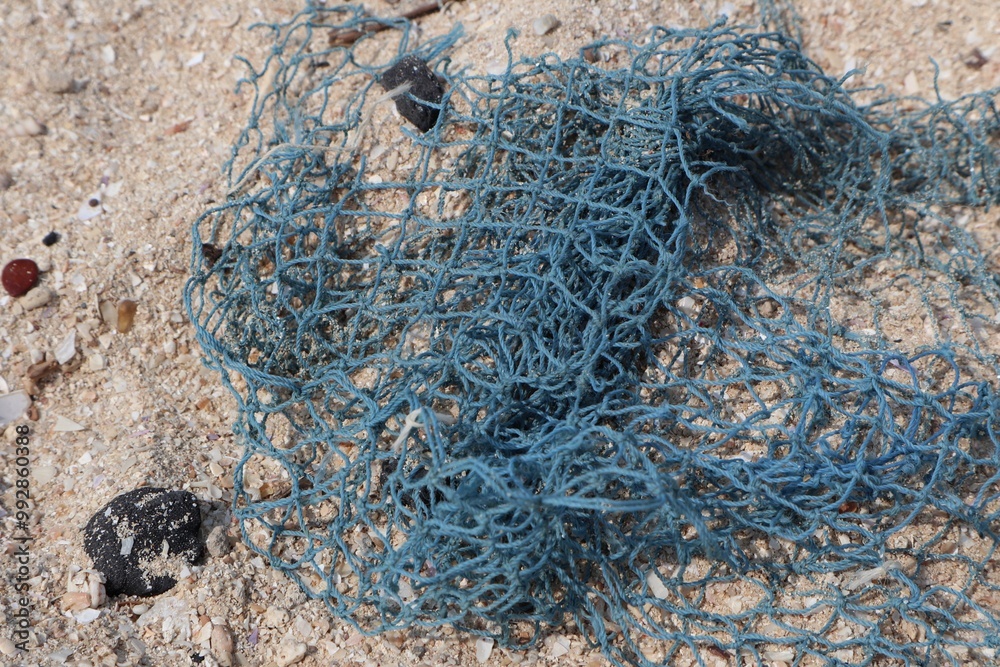 Naklejka premium Close up of pieces of fishing net on beach sand