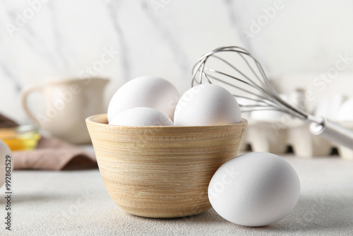 Bowl with raw chicken eggs on white background