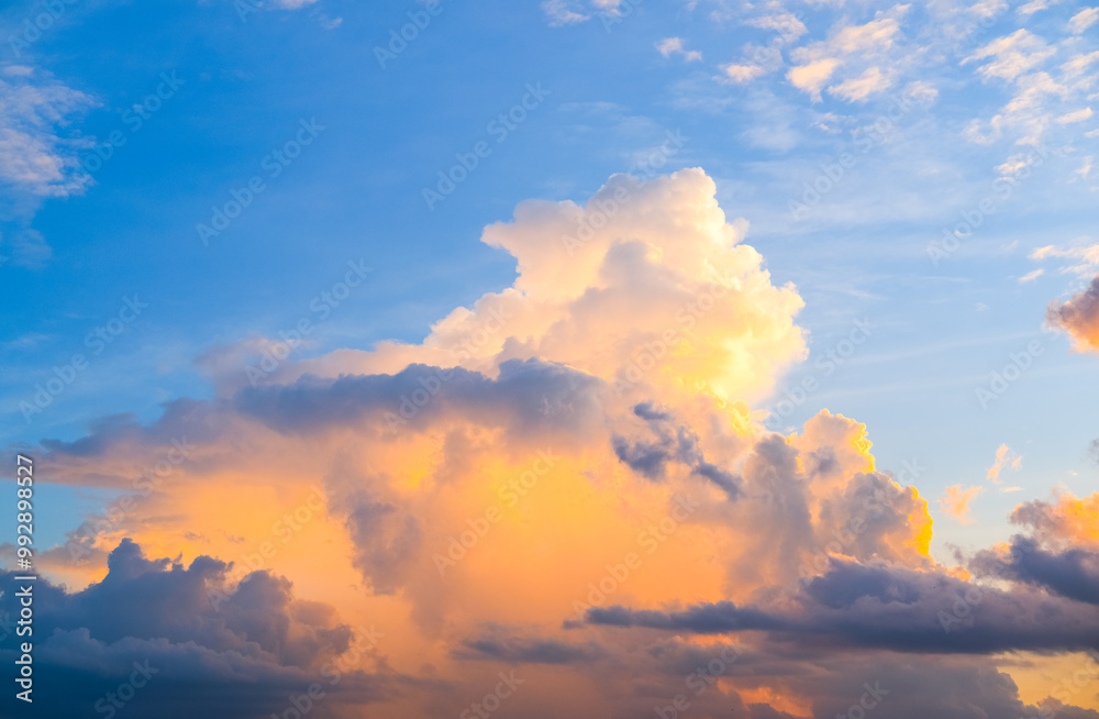 Fluffy clouds glow with warm golden light against a vibrant blue sky, creating a stunning and peaceful scene that captures the beauty of nature’s ever-changing canvas.