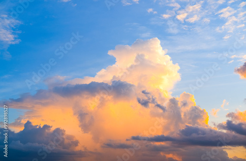 Obraz na płótnie Fluffy clouds glow with warm golden light against a vibrant blue sky, creating a stunning and peaceful scene that captures the beauty of nature’s ever-changing canvas. w salonie