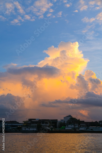 Obraz na płótnie Sunset over Pontianak cityscape at Kapuas River’s edge, with vibrant blue and orange clouds reflecting on the water, capturing the serene beauty of the riverside city. w salonie