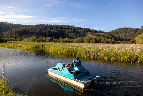 A father and daughter row a paddleboat on a lake while camping. photo