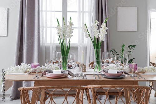 Beautiful table setting with white Gladiolus flowers and burning candles in room