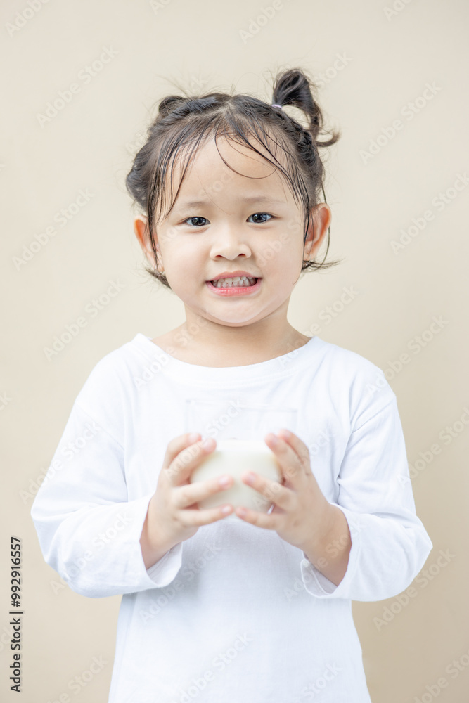 A happy Asian preschool girl holding a glass of milk. A happy Asian preschool girl holding a glass of milk.