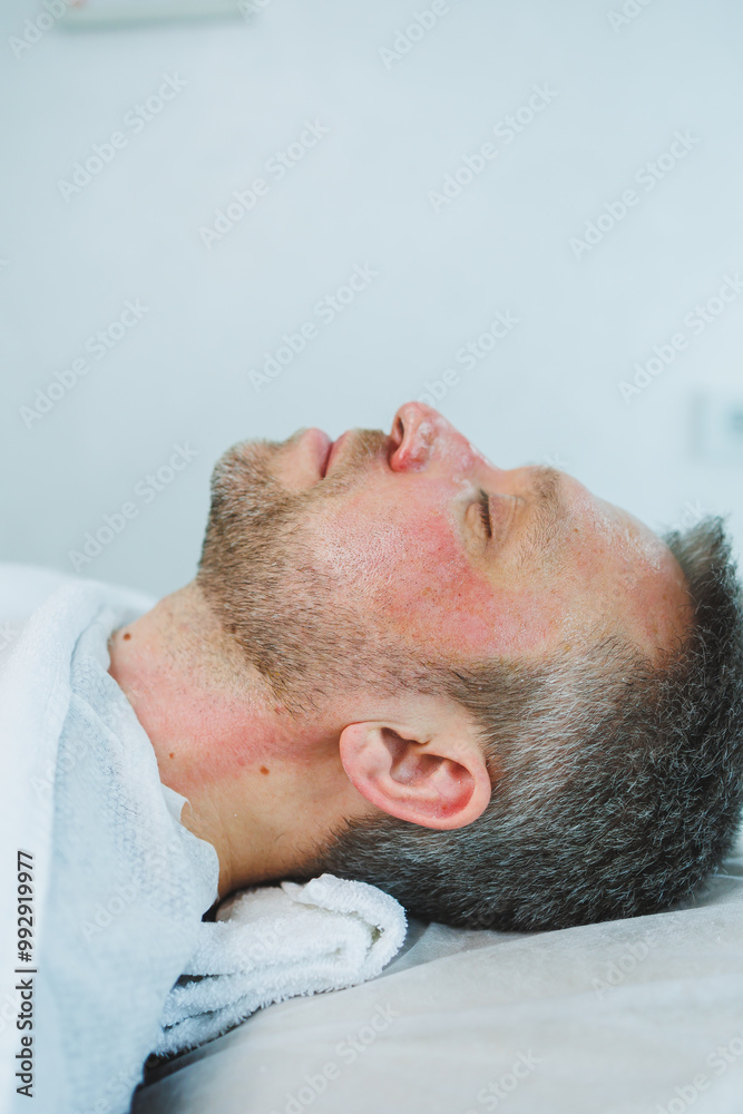 Naklejka premium Male cosmetology. A man lies at a cosmetologist for a facial treatment.