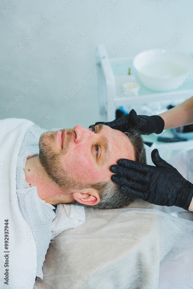 Obraz premium A cosmetologist cleans the skin of a man's face. A man does facial procedures in a cosmetic clinic. Male cosmetology.