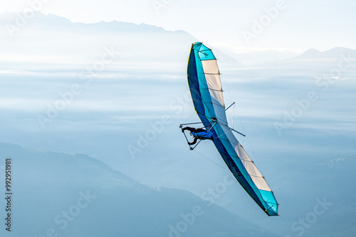 A blue hang-glider in the sky over mountains