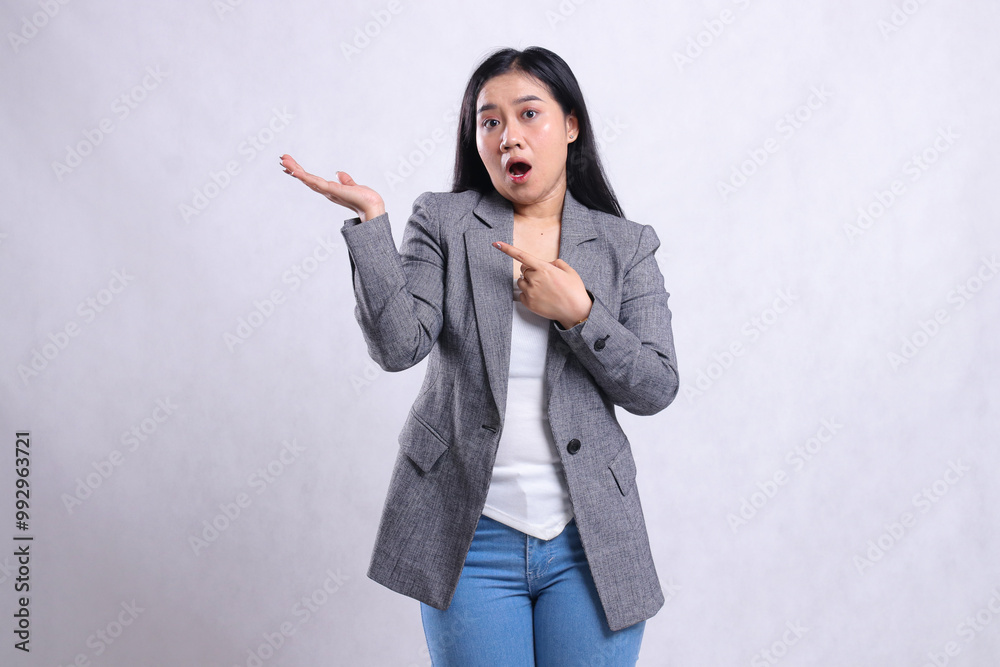 expression of young beautiful ladies surprised hand pointing, presenting to right wearing grey suit and jeans standing isolated on white background. for advertising content, fashion, banner, magazine expression of young beautiful ladies surprised hand pointing, presenting to right wearing grey suit and jeans standing isolated on white background. for advertising content, fashion, banner, magazine